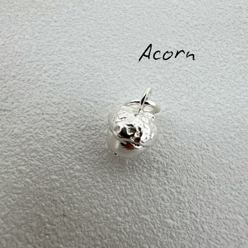 Silver acorn charm on a light gray background