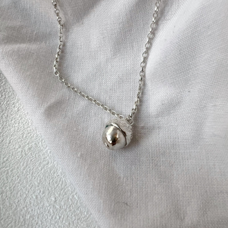 silver acorn necklace on white background