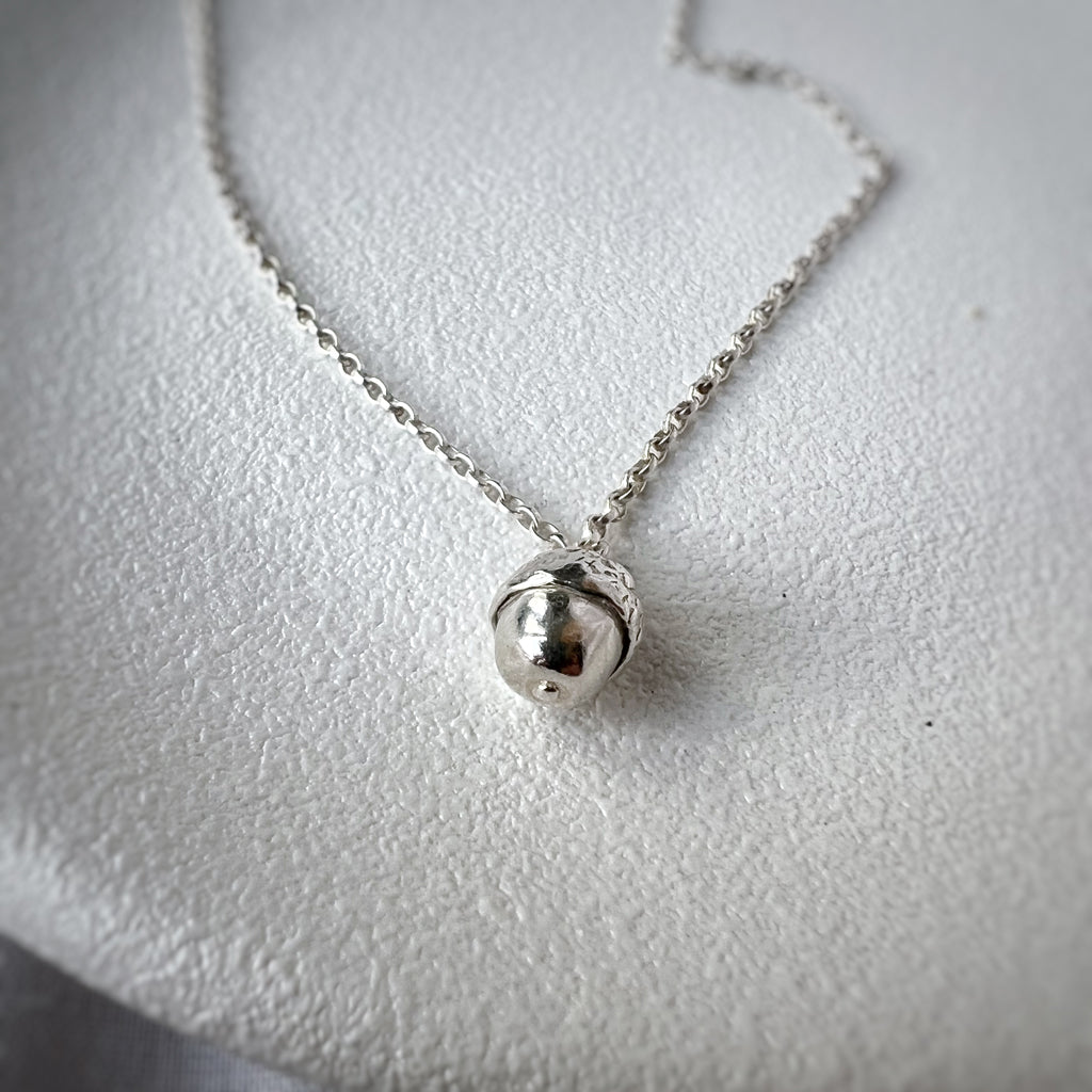 Silver acorn pendant on white plate