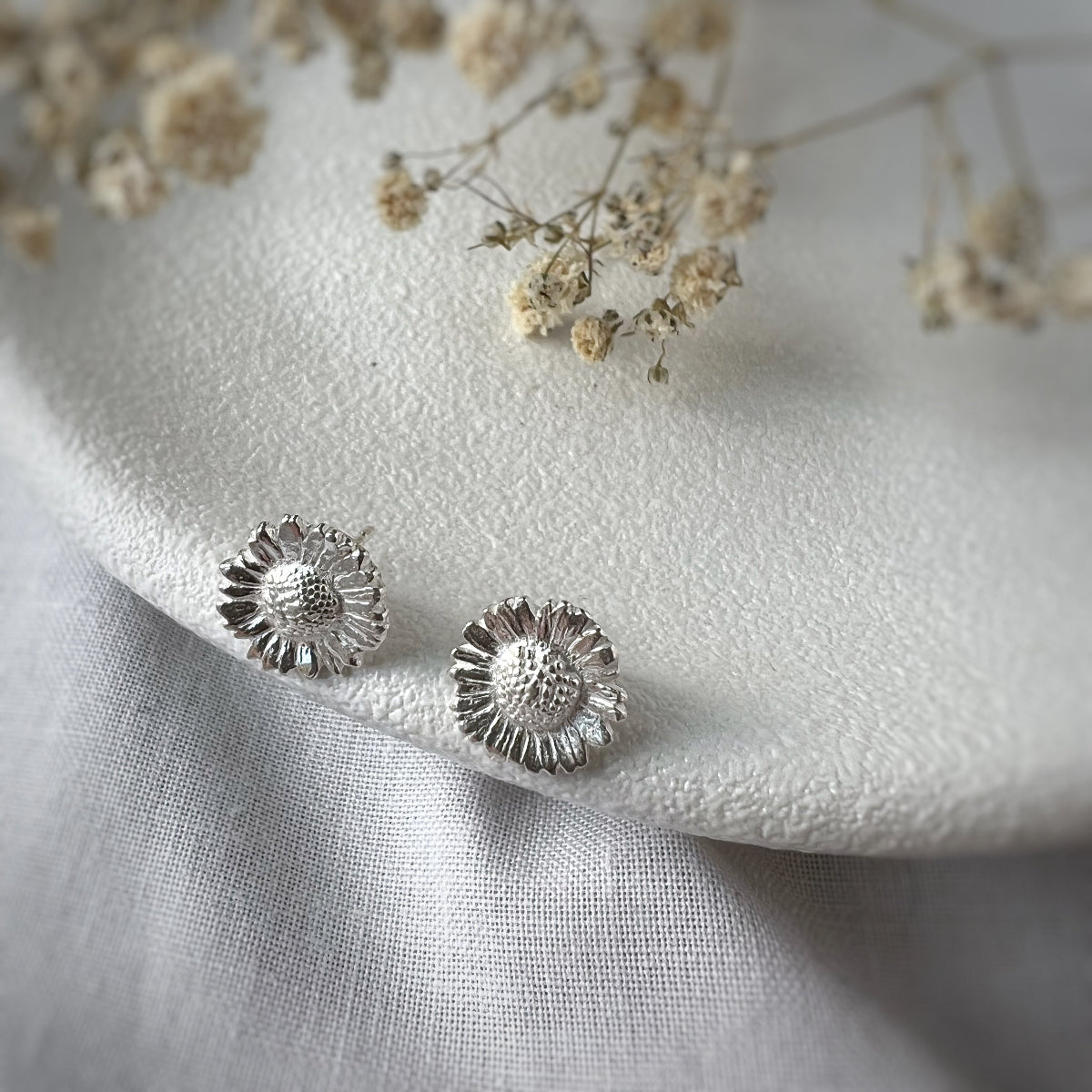 Silver Daisy Earrings on White Plate and White Flowers