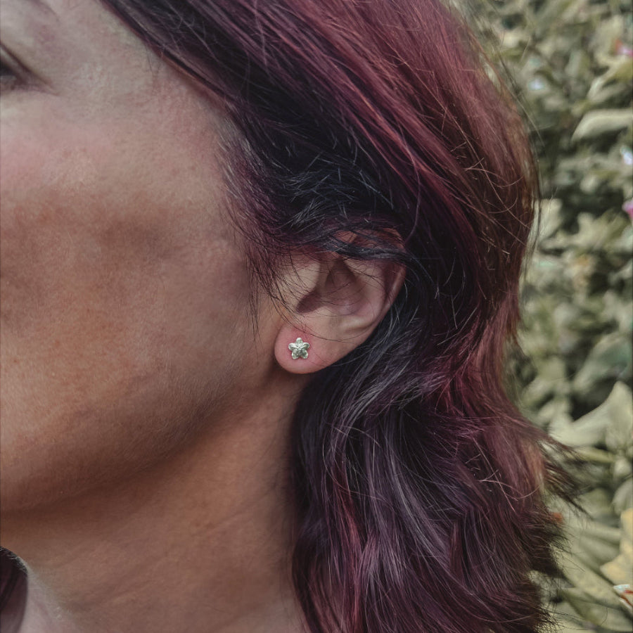 lady wearing small forget me not stud earrings in countryside