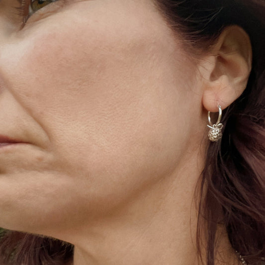 Close up of face wearing silver blackberry earrings
