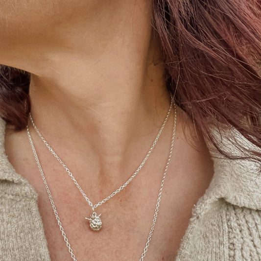 Lady wearing silver blackberry pendant in beige jumper