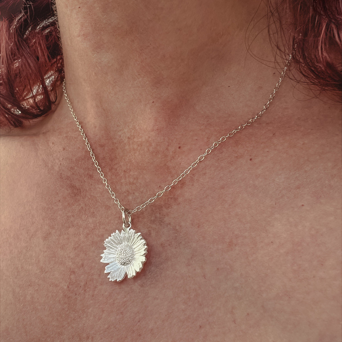 close up of lady wearing silver daisy pendant
