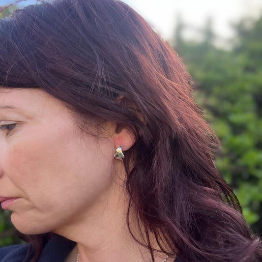 Lady wearing silver oak leaf earrings trees in background