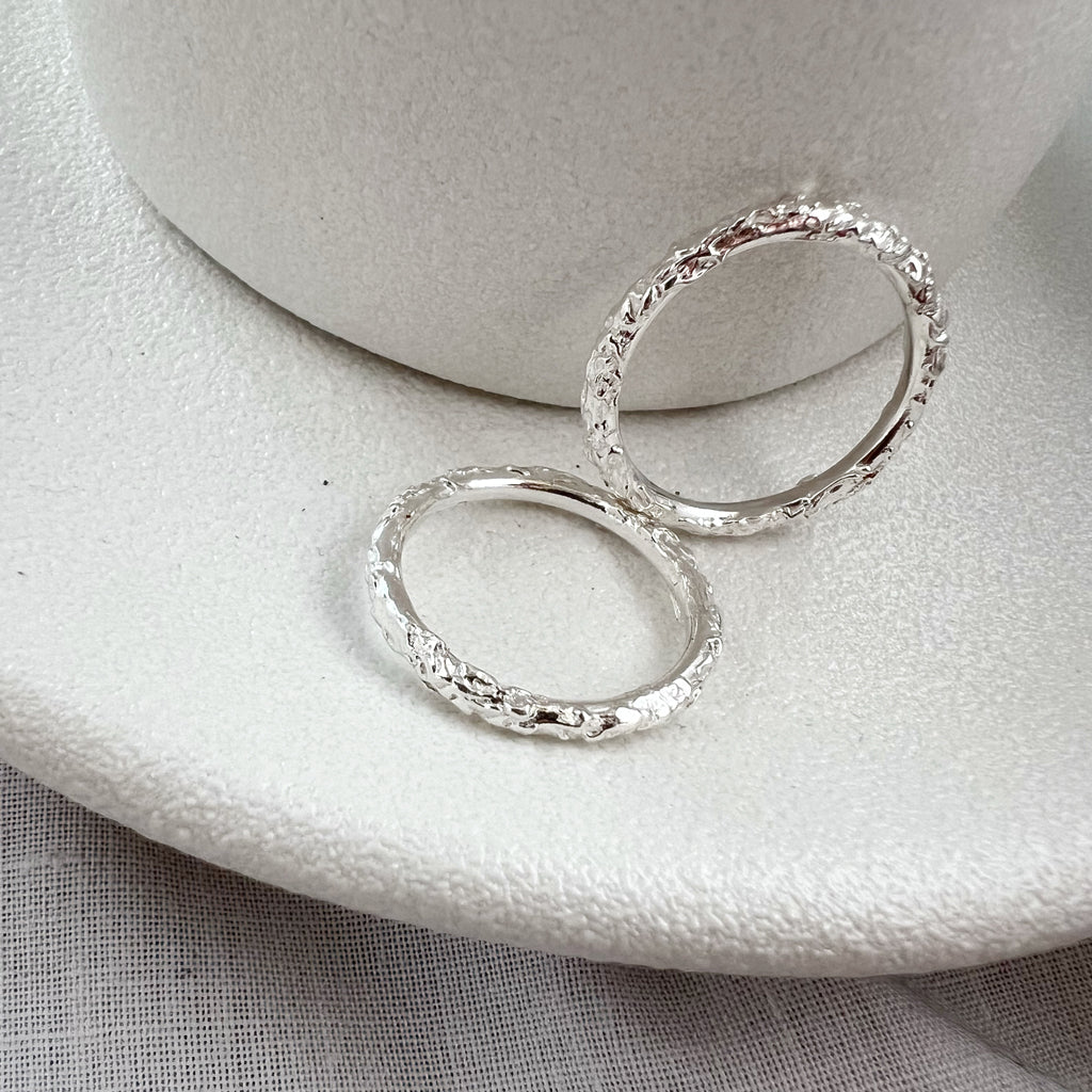 Two textured silver stacking rings on white plate