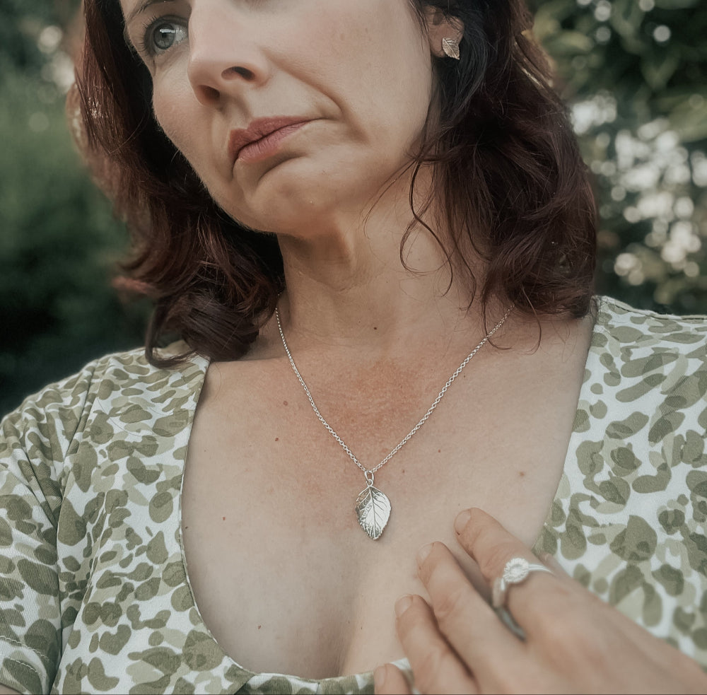 Wearing silver rose leaf pendant and green dress outdoors