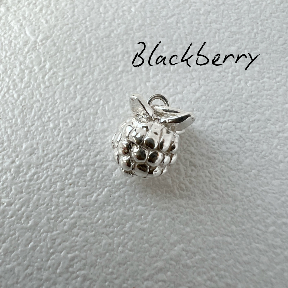 Silver blackberry charm on a light gray background