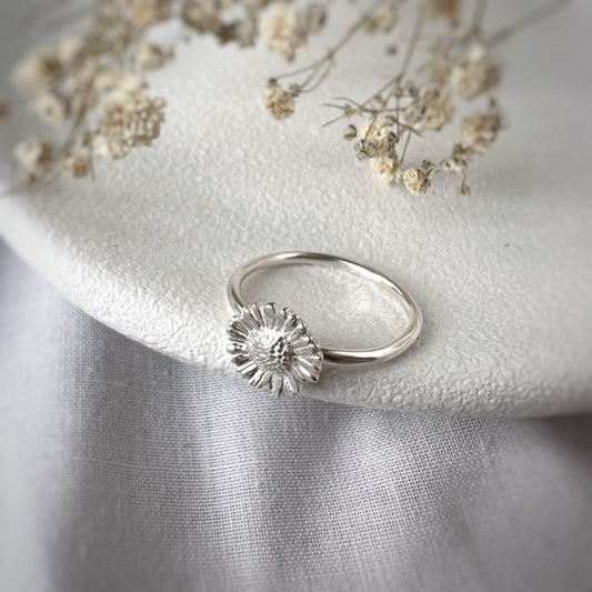 silver daisy ring on white plate ith white flowers