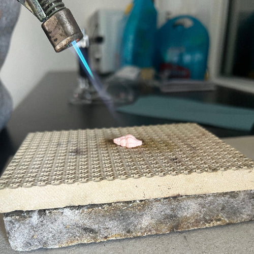 Blow torch firing silver shell on block