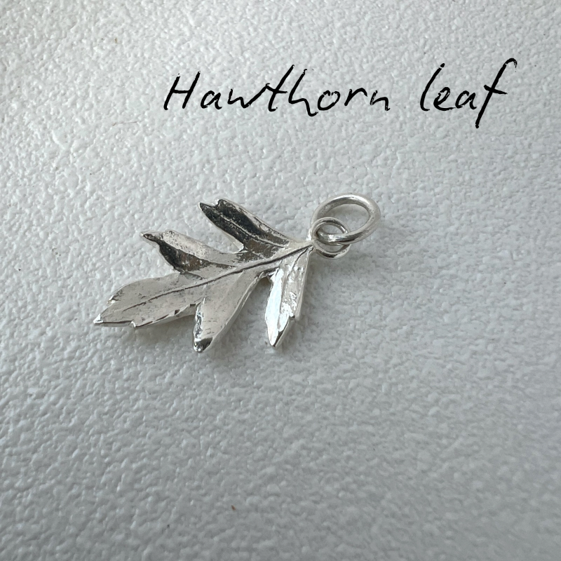 Silver hawthorn leaf pendant on a light gray background