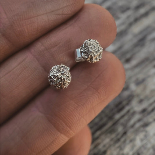 Hand holding small textured silver stud earrings