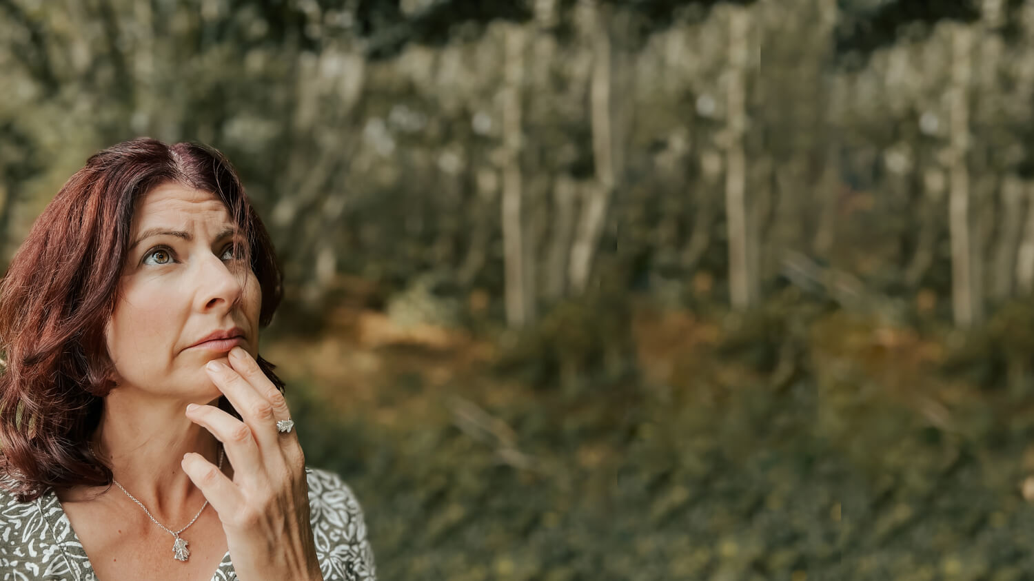 Stairing up into the trees, wearing green dress, silver oak leaf ring and oak leaf pendant