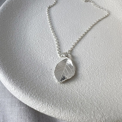 Silver rose leaf necklace on white plate