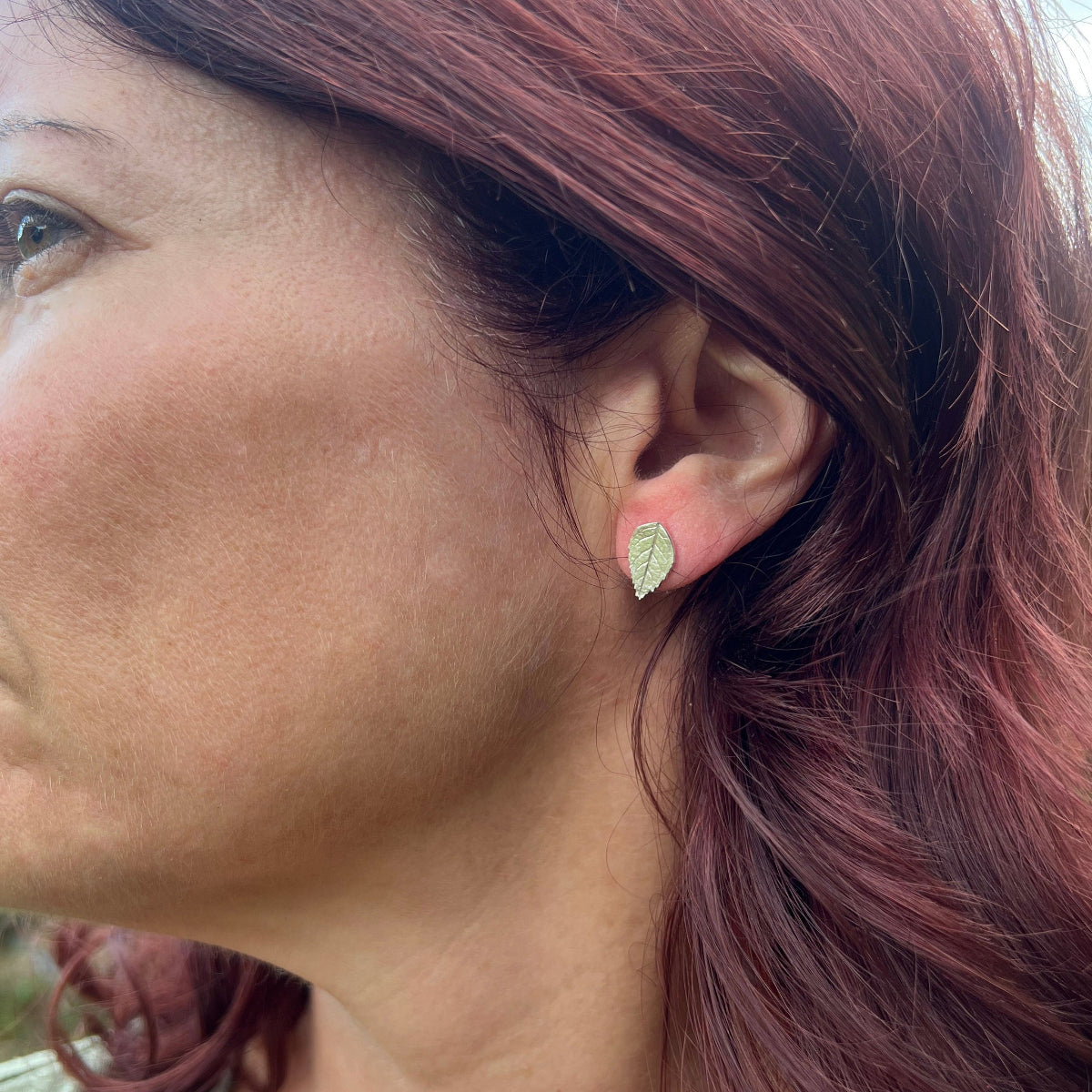 close up of ladies face wearing silver rose leaf studs