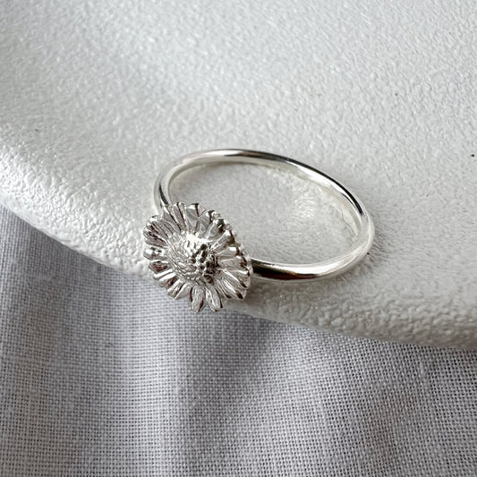 small silver daisy ring on white plate