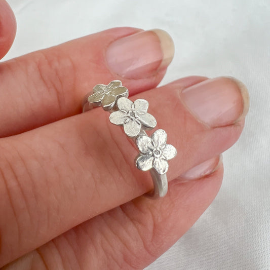 fingers with silver forget me not ring on white background