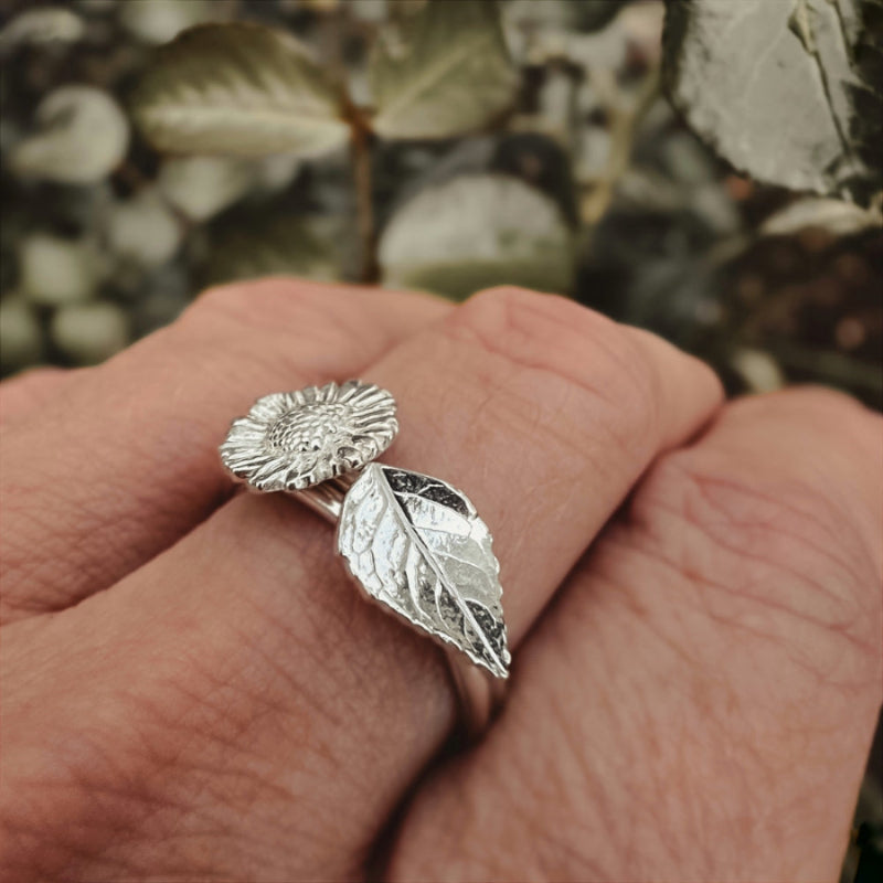 Wearing a daisy and a rose leaf silver rings, rose leaves in background