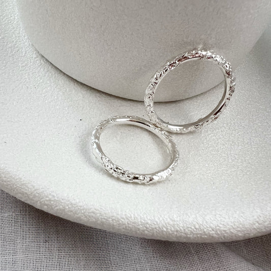 Two textured silver stacking rings on white plate