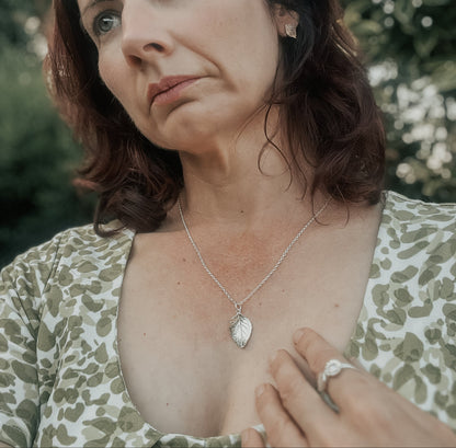 Wearing silver rose leaf pendant and green dress outdoors