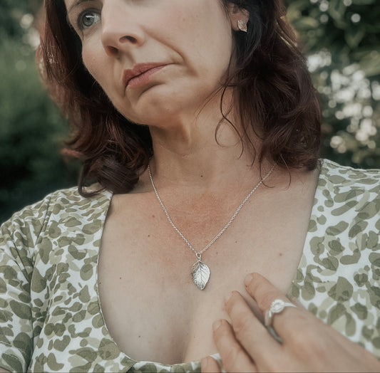 Wearing silver rose leaf pendant and green dress outdoors